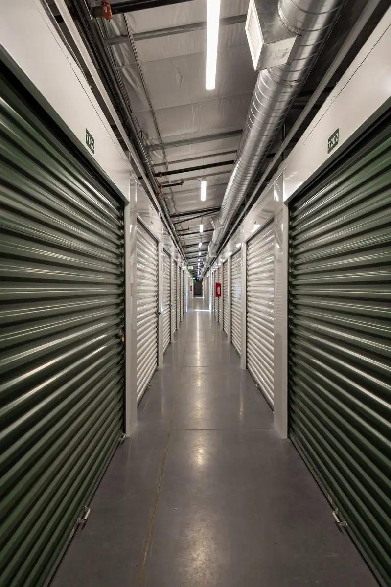 Long interior hallway lined with green roll-up doors in the climate-controlled building