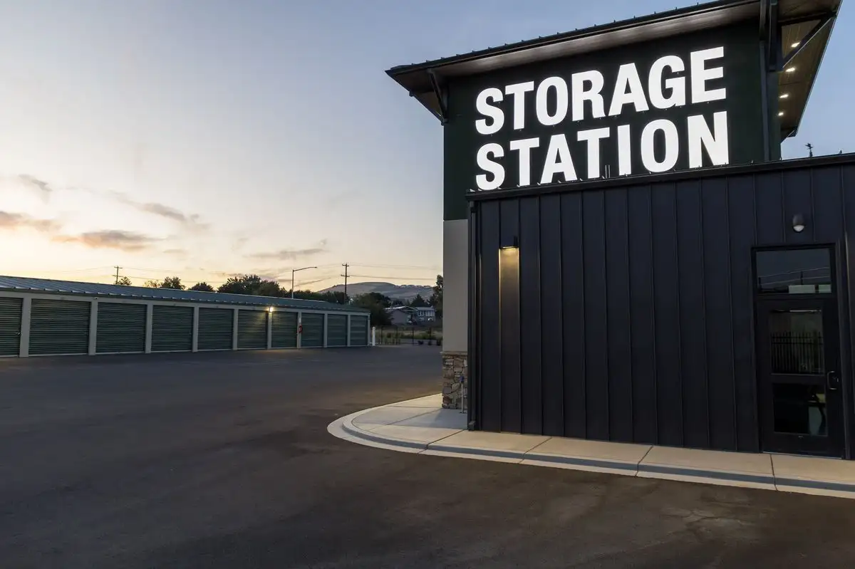 Illuminated STORAGE STATION sign on the side of a building during sunset