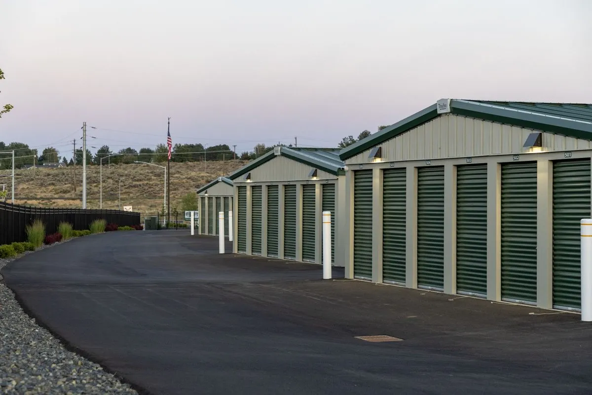 Drive-up storage unit row at Storage Station in Richland, WA — green roll-up doors and clean paved aisles at dusk
